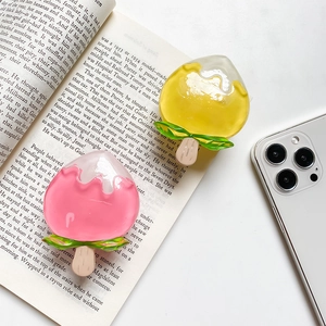 Close-up of cute peach ice cream phone socket grips on an open book background