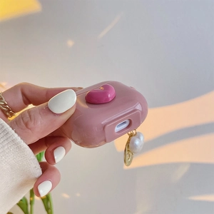 Detail of pink silicone case for AirPods featuring a 3D heart and pearl gold chain charm