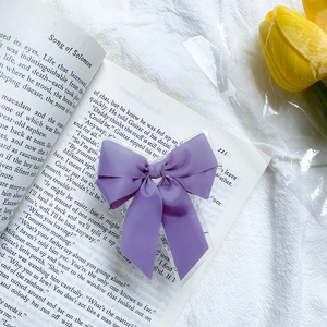 Gros plan du support téléphone nœud violet sur un livre avec tulipe jaune et tissu