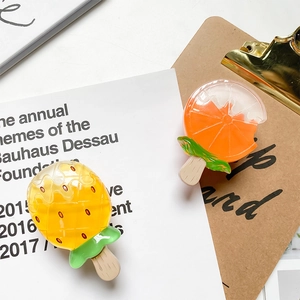 Close-up of creative pineapple and orange popsicle resin phone grips on a desk