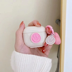 Detail of creamy white AirPods case with pink 3D smile face and round keychain charm