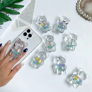 Cute transparent bear phone grip with colorful flower patterns on a white smartphone