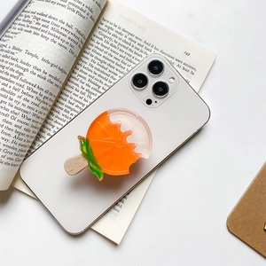 Creative orange popsicle phone grip holder on white smartphone atop a vintage book