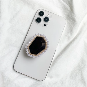 Macro view of luxury phone grip with black faceted gem, pearls and gold rhinestone trim