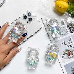 Detailed view of clear bear phone grips with floral resin art on a clean white desk