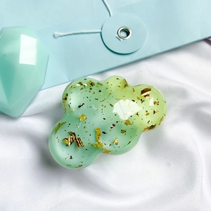 Macro shot of green cloud phone grip with gold foil flakes on white silk fabric