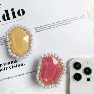 Close-up of gem-style phone grips with glitter resin, pearls, and rhinestones