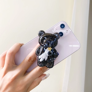 Detail of 3D bear phone grip with glitter finish and astronaut charm on purple phone