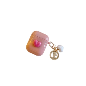 Pink glossy AirPods case with 3D heart, gold coin pendant and plush charm on white background