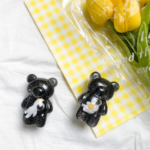 Detailed close-up of glittery black bear-shaped phone grips with cute 3D astronaut motifs
