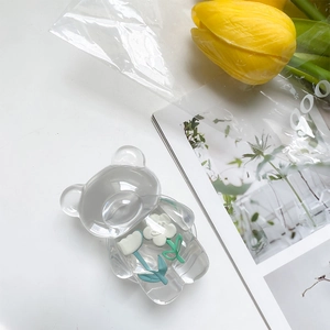 Detail of transparent bear phone grip with embedded white and blue tulips in resin