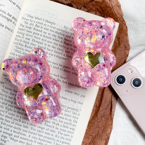 Dettaglio macro del supporto per telefono orso carino con paillettes su un libro