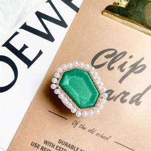 Close-up of emerald green gem phone grip with pearl border on a vintage clipboard