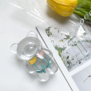 Macro detail of clear bear phone grip with yellow and pink tulips inside on white desk