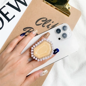 Detail of elegant gem and pearl cell phone grip stand on a white smartphone back