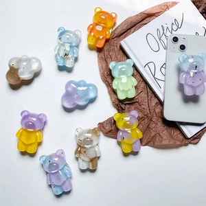 Collage of colorful glitter bear and cloud cell phone socket stands on white desk