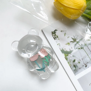 Macro detail of clear acrylic bear phone grip featuring a pink floral inlay design