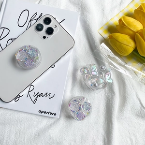 Iridescent laser flower and butterfly phone grips on white textured fabric backdrop