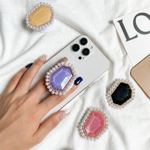 Macro view of crystal gem phone grips with pearl borders and gold accents on a white phone