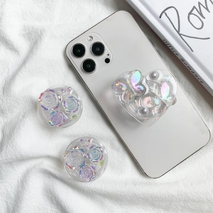 Close-up of holographic heart and floral phone grips with pearl and butterfly details