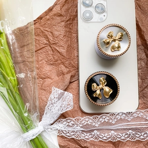Detailed view of 3D metallic bow phone grip stand attached to a white smartphone back