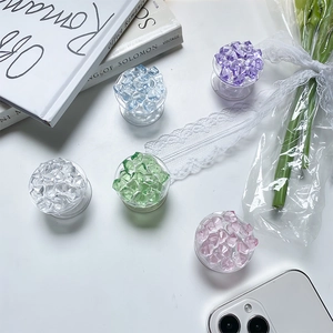 Top view of five colorful ice-crystal collapsible phone grips on a white aesthetic background