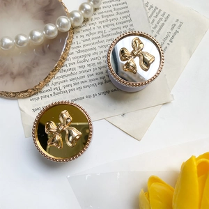Detailed close-up of golden bow-shaped griptok with metallic mirror finish on flat lay