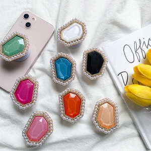 Macro view of crystal gemstone phone grips with rhinestones and pearls on white fabric