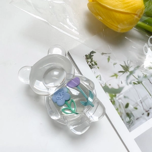 Macro detail of clear bear phone grip featuring 3D embedded blue and purple flowers