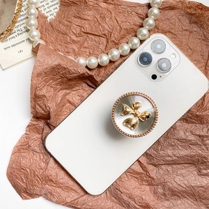 Creative electroplated metal bowknot phone grip holder on white smartphone back