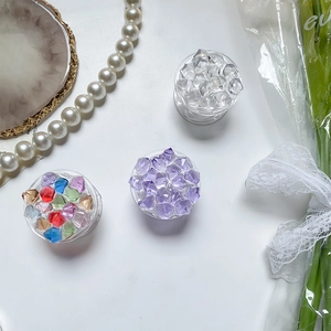 Detail of colorful crystal stone Griptok phone grips on an elegant white tabletop