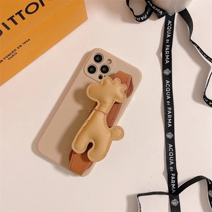 Détail de coque iPhone avec dragonne 3D girafe en cuir beige sur fond de couleur crème