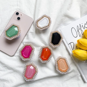 Macro shot of colorful gem phone grips with pearl and rhinestone edges on white cloth