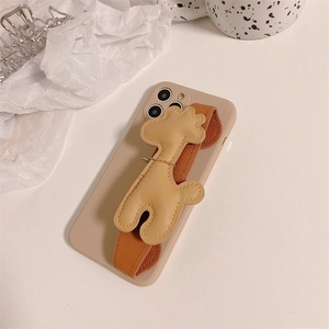 Détail du bracelet en tissu marron et du charm de chien mignon sur la coque iPhone