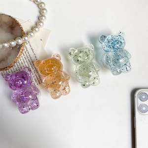 Macro detail of translucent glitter bear phone grips in purple, orange, green and blue