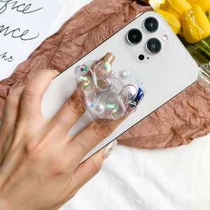 Detail of heart-shaped phone grip with iridescent butterflies and pearls on a white phone