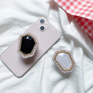 Macro shot of stylish black and pearl white gem phone grips with rhinestones on white fabric