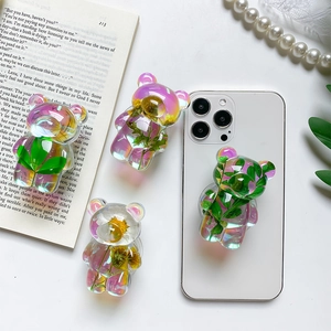 Detailed view of four bear-shaped resin phone grips with embedded dried flowers and leaves