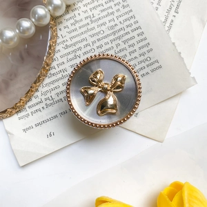 Macro shot of electroplated bow phone stand with vintage concentric textures and gold beads