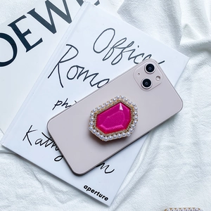 Detail of rose red hexagon gemstone phone grip with pearls on a purple device