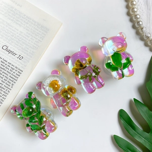 Close-up of four bear-shaped resin phone grips with colorful laser finish and dried flowers