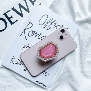 Macro detail of a pink glitter gem phone grip with pearl and rhinestone inlay on a phone