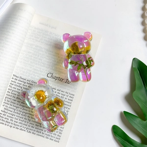 Detail of bear-shaped resin phone grip with colorful laser finish and embedded real flowers