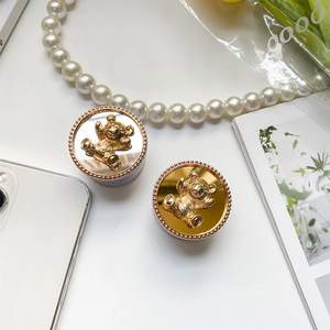 Detailed view of 3D bear phone grips in gold and silver mirror finishes on white background