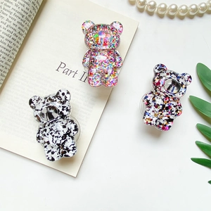 Detailed macro view of three cute glitter bear phone socket stands on a white desk