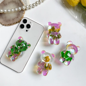 Macro detail of holographic bear phone socket featuring embedded real dried flowers