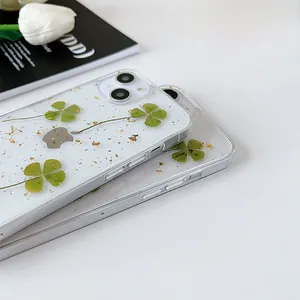 Dettaglio custodia iPhone trasparente con veri quadrifogli essiccati e foglia d'oro