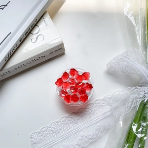 Close-up of red acrylic ice stones in a clear tray on a decorative white table