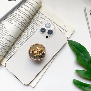 Golden 3D bear phone socket stand with pearl-style mirror base on a white smartphone