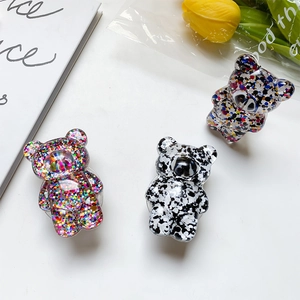 Three bear-shaped phone grips with glitter sequins shown in a lifestyle setup